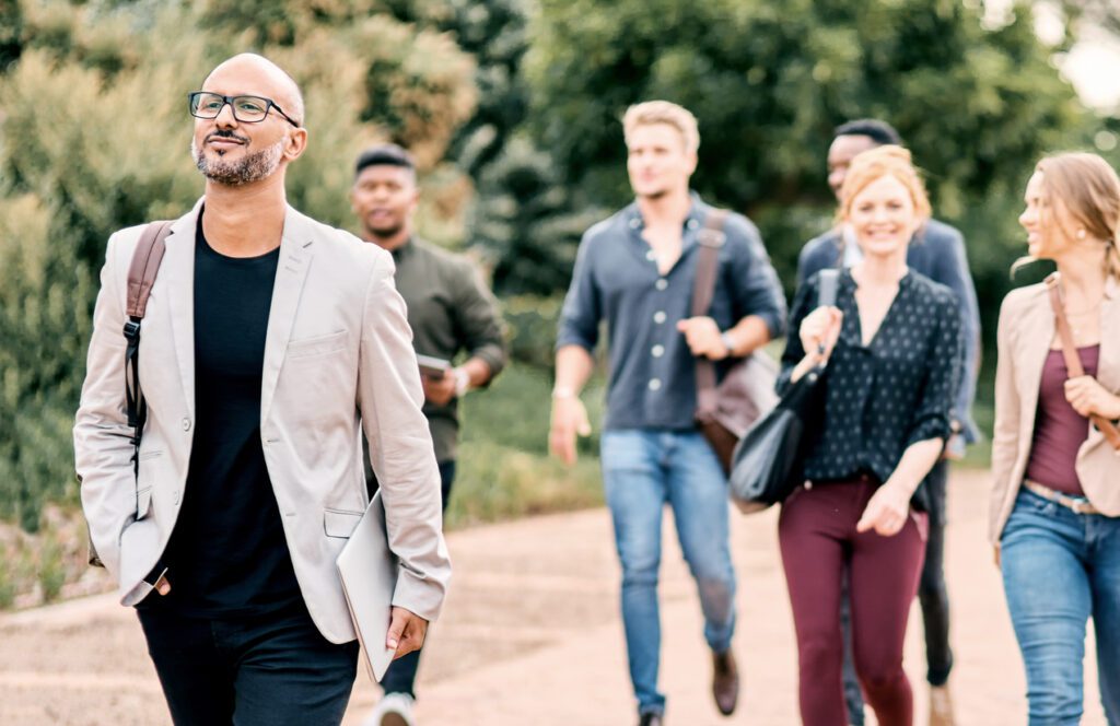 Shot of a confident mature businessman walking through the city with a young team behind him